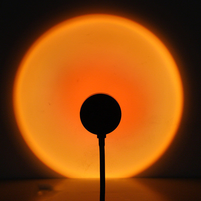 Sunset projection lamp casting a warm glow, creating a cozy atmosphere with soothing orange tones.