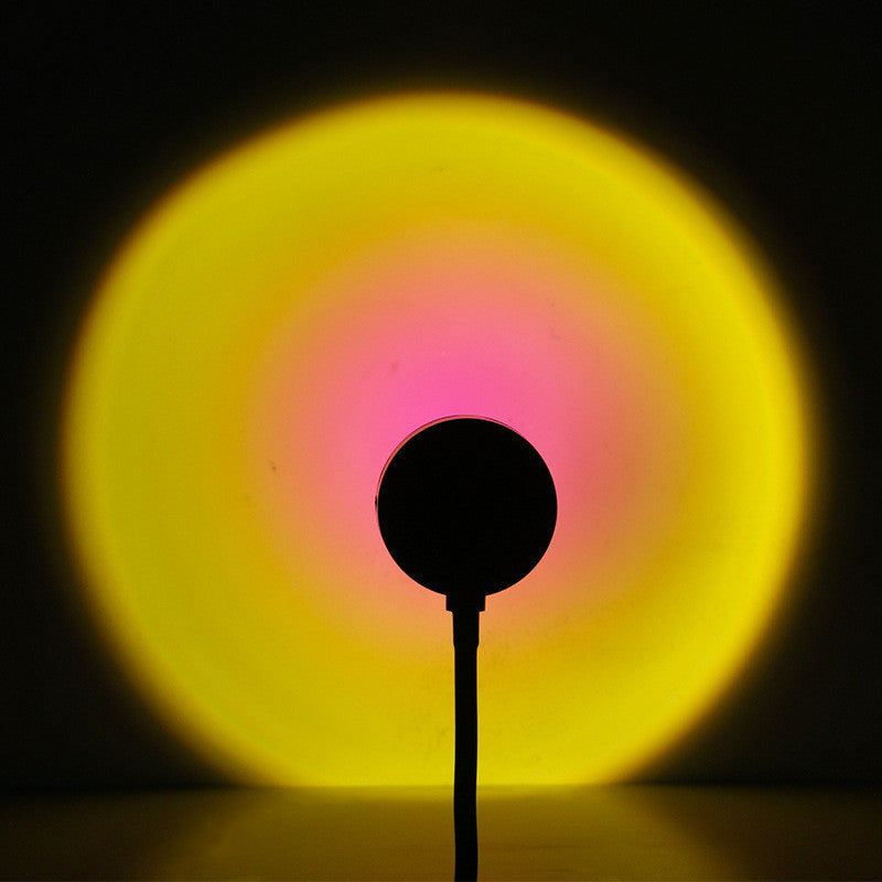 Sunset projection lamp casting a warm yellow and pink light, creating a cozy atmosphere on a wall.