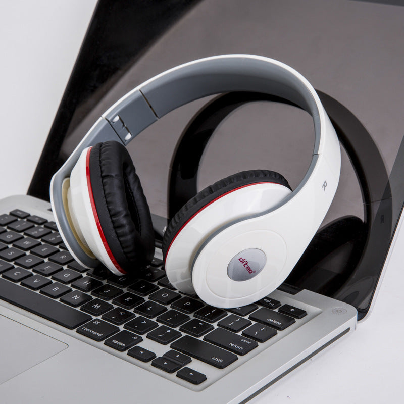 Wired gaming headphones with heavy bass resting on a laptop keyboard, showcasing a stylish design.