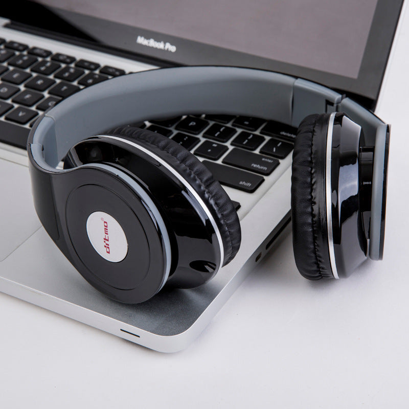 Wired gaming headphones with heavy bass resting on a laptop keyboard, stylish design in black and grey.